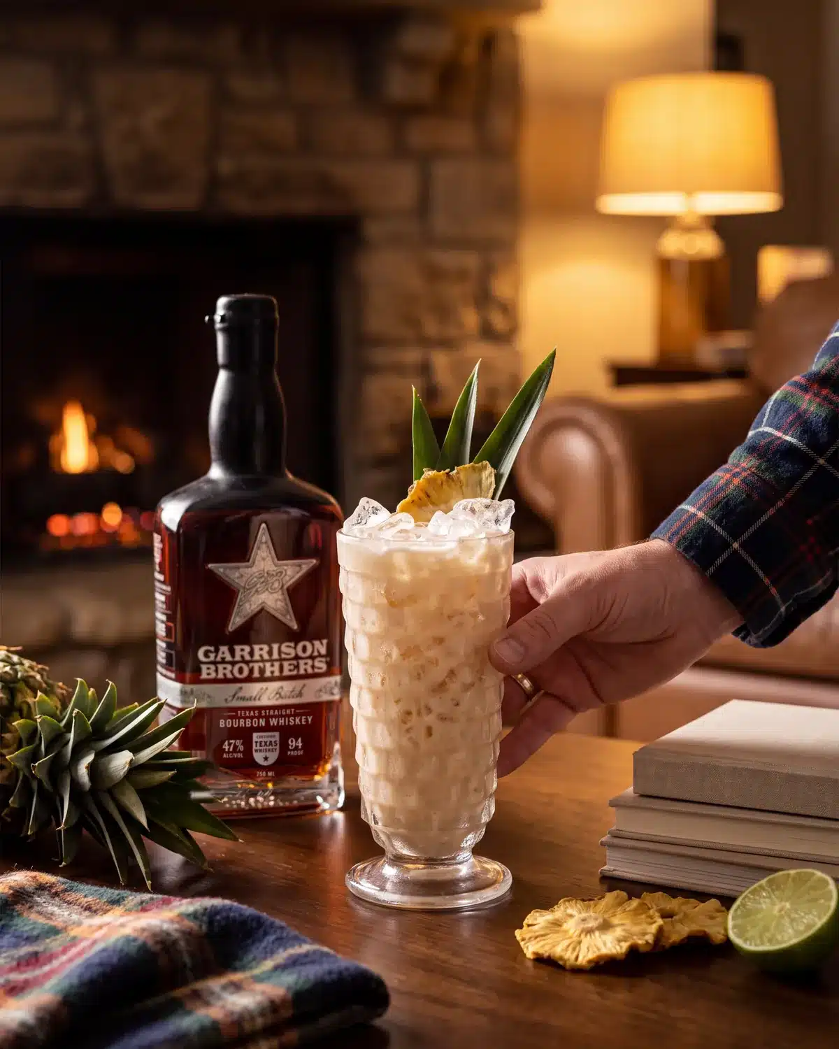 Hye Tai bourbon cocktail by a stone fireplace with a bottle of Garrison Brothers Small Batch Bourbon