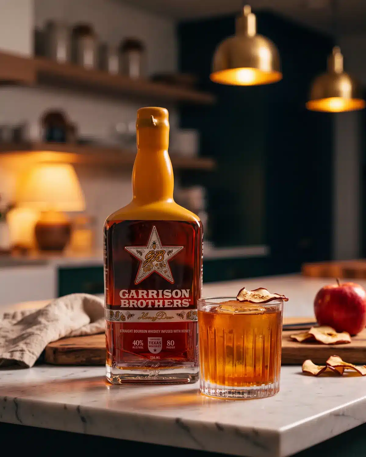 Bourbon Apple Betty bourbon cocktail on a kitchen counter with a bottle of Garrison Brothers HoneyDew Bourbon