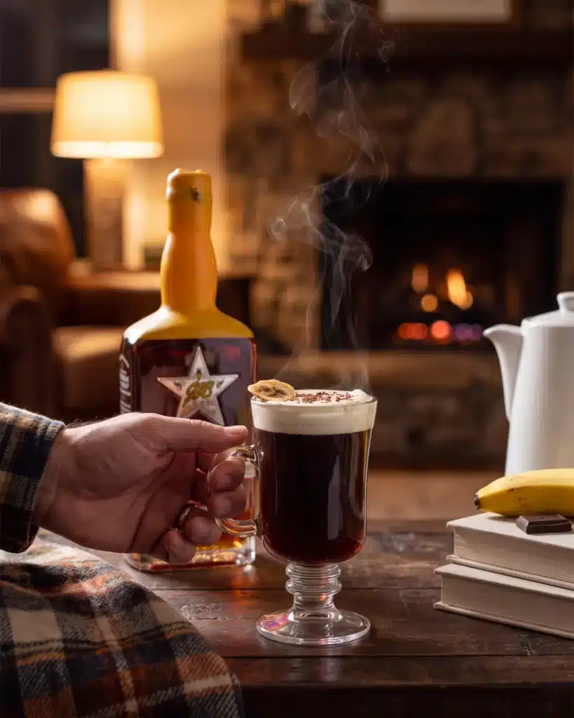 New Year, Same Me bourbon cocktail by a stone fireplace with a bottle of Garrison Brothers HoneyDew Bourbon