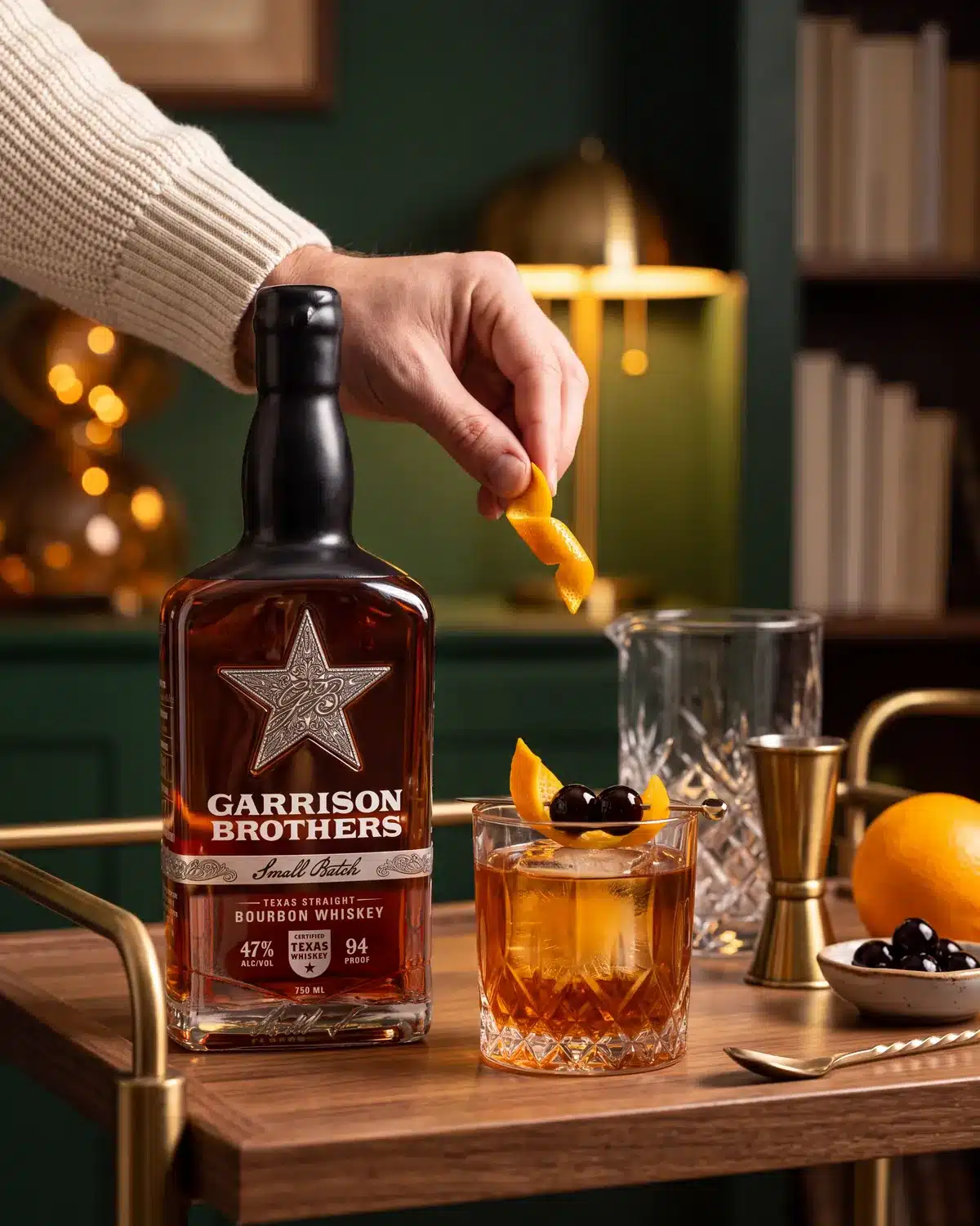 Classic Old Fashioned bourbon cocktail on a home bar cart with a bottle of Garrison Brothers Small Batch Bourbon