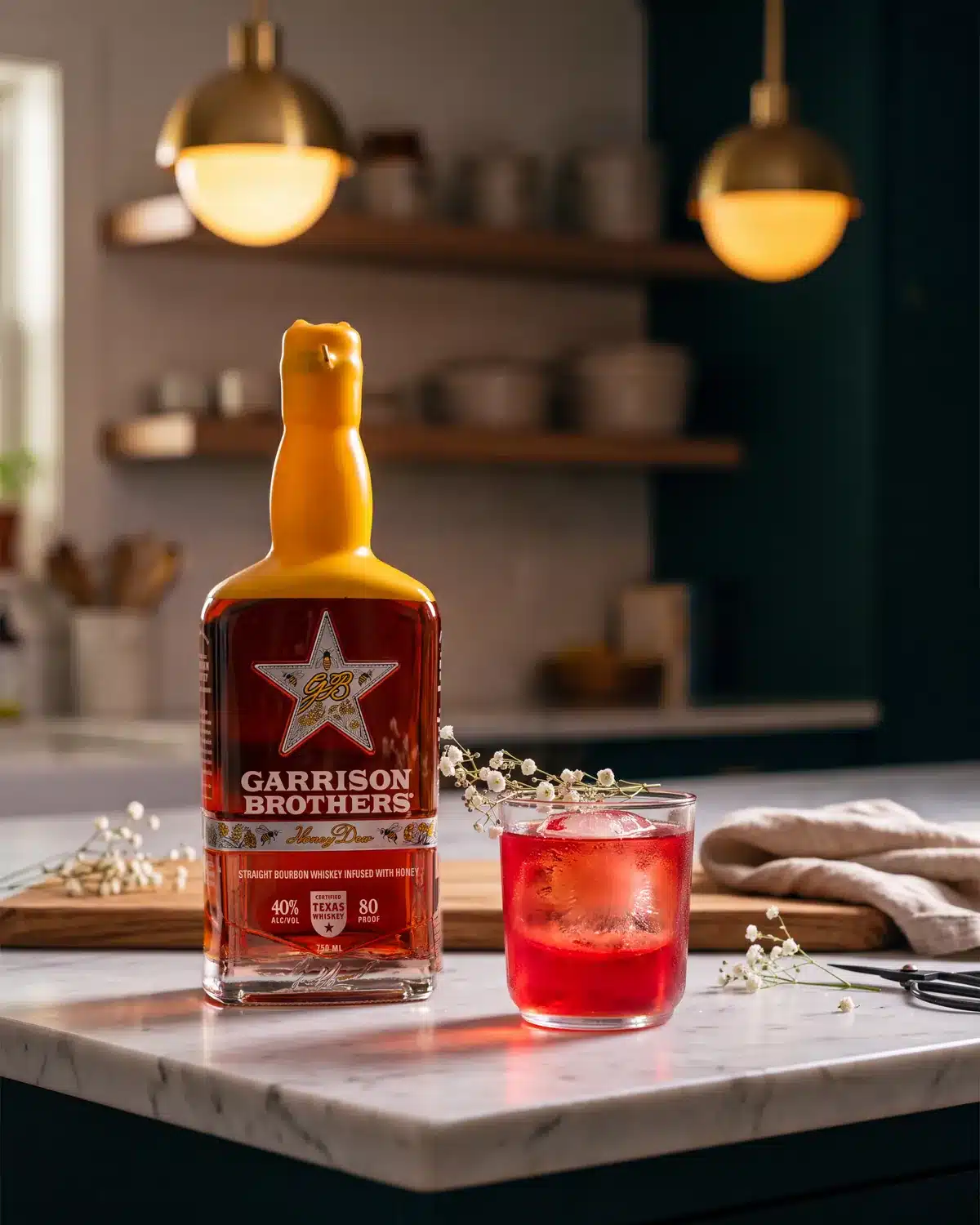 Old Fashioned Sloe-Cookin' bourbon cocktail on a kitchen counter with a bottle of Garrison Brothers HoneyDew Bourbon