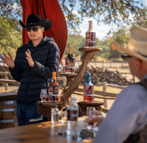Outdoor tasting experience at Hye Reserve, featuring a private bar with Garrison Brothers bourbon bottles and seating under a shaded structure in the Texas Hill Country.
